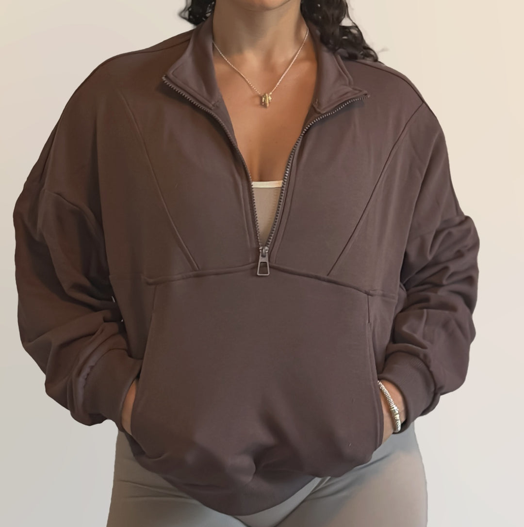 Person wearing a brown half-zip sweatshirt on a plain background