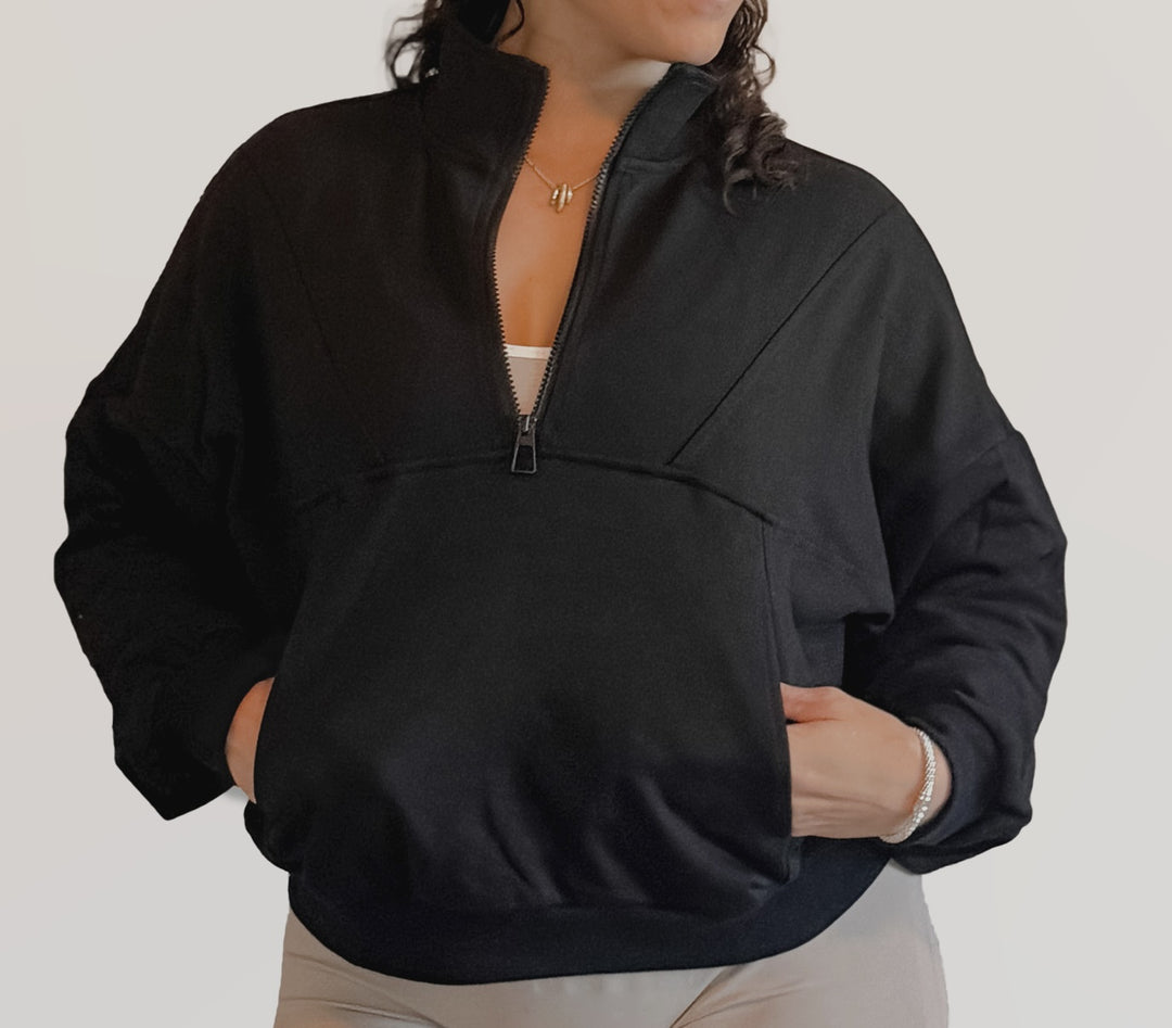 Person wearing a black half-zip jacket on a plain background