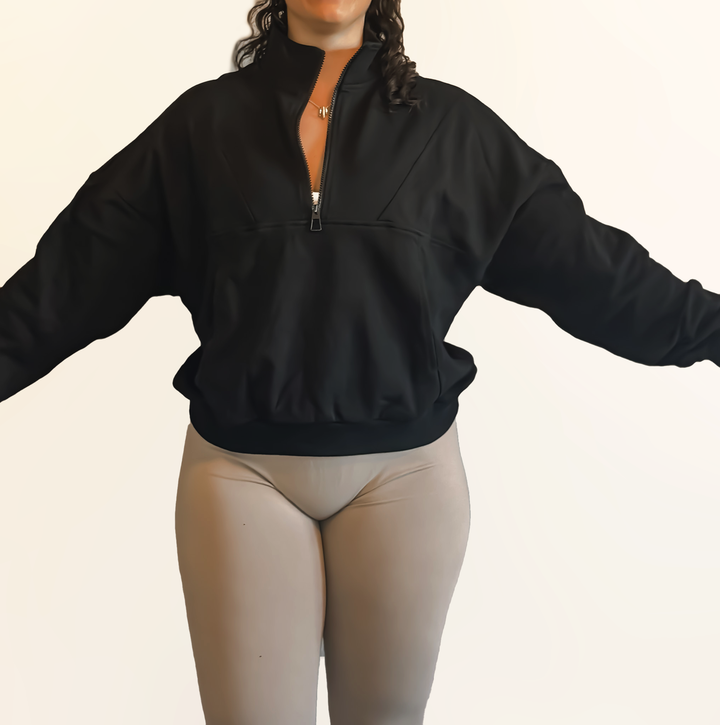Person wearing a black quarter-zip sweatshirt on a beige background